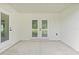 Covered patio with concrete floor and white walls, featuring double glass doors to backyard at 8293 Se 158Th St, Summerfield, FL 34491