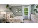 A cozy bedroom featuring a comfortable bed, serene wall art, and a view of the greenery outdoors at 8510 Las Palmas Way, Wildwood, FL 34785