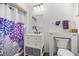 Bright bathroom features a white vanity, drawers, and cabinet toilet with purple floral shower curtain at 9021 Sw 108Th Pl, Ocala, FL 34481