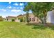 Backyard view of home featuring a well-maintained lawn, mature trees, and an inviting outdoor patio area at 9266 Sw 91St Cir, Ocala, FL 34481