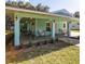 Inviting covered front porch with teal columns, outdoor lighting, and comfortable seating area at 9330 Se 106Th Pl, Belleview, FL 34420