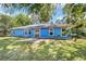 Rear exterior showcasing a blue house with sliding glass doors and a concrete patio at 11 Se Fir Trail Trak, Ocala, FL 34472
