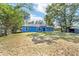 Expansive backyard featuring a blue home, mature trees and lush green grass at 11 Se Fir Trail Trak, Ocala, FL 34472