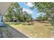 Large backyard surrounded by lush green trees showcasing a blue house at 11 Se Fir Trail Trak, Ocala, FL 34472