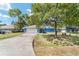 Front exterior featuring a spacious driveway, blue home, and mature trees at 11 Se Fir Trail Trak, Ocala, FL 34472