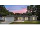 Charming single-story home with a two-car garage and manicured lawn under a beautiful twilight sky at 1143 Sw Tamiami Pl, Dunnellon, FL 34431