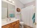 Bright bathroom featuring a wood vanity, tub with shower, and charming sun decor at 12804 Se 90Th Court Rd, Summerfield, FL 34491