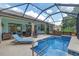Relaxing pool area with a screened-in enclosure, lounge chairs, and blue tile accents for a luxurious retreat at 12804 Se 90Th Court Rd, Summerfield, FL 34491