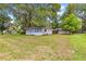 Exterior view of a quaint, white house with green grass and mature trees in a peaceful, quiet neighborhood at 1405 Ne 55Th St, Ocala, FL 34479