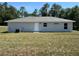 A simple home with a cozy backyard on a sunny day with a grey exterior at 14443 Sw 21St Pl, Ocala, FL 34481