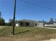 Single-story home with a well-manicured lawn and attached garage, with lush surrounding trees and a blue sky at 14443 Sw 21St Pl, Ocala, FL 34481