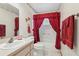 Pink bathroom with tiled floor, decorative floral accents, and bathtub with red shower curtain at 2008 Tweed Ct, Leesburg, FL 34788