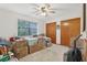 Cozy bedroom with neutral carpet, ceiling fan, large window and wood-paneled closet doors at 2008 Tweed Ct, Leesburg, FL 34788