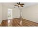 Bedroom showcasing hardwood floors, ceiling fan, view into the bathroom, with neutral wall paint at 2208 Orkney Dr, Leesburg, FL 34788