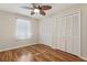 Bedroom with wood flooring, ceiling fan, and spacious closets, perfect for relaxing or storage at 2208 Orkney Dr, Leesburg, FL 34788