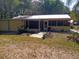 Cozy yellow home featuring a screened porch, metal roof, and lush greenery creating a peaceful and inviting outdoor space at 22736 Sw 117Th St, Dunnellon, FL 34431