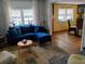 Cozy living room features a plush blue sofa, large windows and laminate flooring at 22736 Sw 117Th St, Dunnellon, FL 34431
