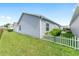 Exterior view of home featuring neutral siding and a white picket fence around the green lawn at 2296 Sheehan St, The Villages, FL 32163