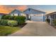 Charming single-story home with a two-car garage, lush landscaping, and a concrete driveway, set against a colorful sunset at 2296 Sheehan St, The Villages, FL 32163
