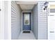 Close-up of the light gray home's front door with a decorative glass window, welcome mat and house numbers at 2296 Sheehan St, The Villages, FL 32163