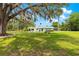 A single-story home with turquoise accents, a large lawn with mature trees, and a circular driveway at 2475 Sw 7Th Ave, Ocala, FL 34471