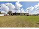View of the backyard showing the house with a screened-in porch overlooking the green space and some cloud coverage at 4331 Se 106Th Pl, Belleview, FL 34420