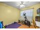 Bedroom with a fan, light yellow walls, an elliptical machine, and wood floors at 705 Washington Ave, Eustis, FL 32726