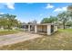 Single-story home with a screened porch, covered carport, and lush greenery at 705 Washington Ave, Eustis, FL 32726