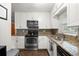 Charming kitchen with stainless steel appliances, granite counters and backsplash plus white cabinets at 705 Washington Ave, Eustis, FL 32726