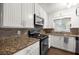 Kitchen with stainless steel appliances, granite counters and backsplash, and white cabinets at 705 Washington Ave, Eustis, FL 32726
