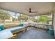 Screened porch features a ceiling fan and blue outdoor furniture on an eye-catching patterned rug at 705 Washington Ave, Eustis, FL 32726