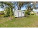 Exterior view of the shed, with a painted door and surrounded by lush foliage and trees at 705 Washington Ave, Eustis, FL 32726