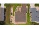 Aerial view of a charming home showcases a well-manicured lawn, landscaped garden beds, and a brown roof at 11871 Se 91St Cir, Summerfield, FL 34491