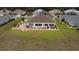 Aerial view of a sunny back patio enclosed with large windows, meticulously maintained garden beds, and a lush green lawn at 11871 Se 91St Cir, Summerfield, FL 34491
