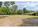 Open backyard featuring a lush green lawn, mature trees, and a view of the house at 12495 Sw 66Th St, Ocala, FL 34481