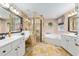 Elegant bathroom with stone tile, double vanity, glass enclosed shower and a corner soaking tub at 12495 Sw 66Th St, Ocala, FL 34481