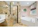 Bathroom featuring stone tile in the glass enclosed shower and a corner tub with natural light from the window at 12495 Sw 66Th St, Ocala, FL 34481