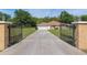 Gated home featuring a long driveway leading to a tan house with an attached garage at 12495 Sw 66Th St, Ocala, FL 34481