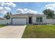 Charming single-story home featuring a well-manicured lawn, white exterior, and an attached two-car garage at 14055 Sw 30Th Terrace Rd, Ocala, FL 34473