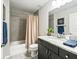 Bathroom with granite counters, tiled shower with curtain, and decorative painting at 16192 Se 104Th Ter, Summerfield, FL 34491