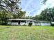 Charming single-story home with a light blue exterior, a screened porch, and a metal roof surrounded by lush greenery at 2409 Nw 7Th St, Ocala, FL 34475