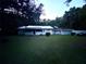 A single-story home with a metal roof and a screened porch, set against a backdrop of trees and a spacious front lawn at 2409 Nw 7Th St, Ocala, FL 34475