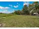 Large backyard with a grassy field, mature trees, and a camper in the distance under a blue sky at 531 Ne 142Nd Ave, Silver Springs, FL 34488