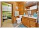 Rustic bathroom features wood paneling, toilet, towel rack, sink with wooden cabinetry, and a framed mirror at 531 Ne 142Nd Ave, Silver Springs, FL 34488