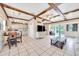 Open concept living area boasts tile floors, wood beam ceilings, and a view of the kitchen and back deck at 531 Ne 142Nd Ave, Silver Springs, FL 34488