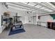 Organized garage boasts epoxy flooring, a golf cart, shelving, and tools, showcasing functionality and convenience at 6051 Sw 93Rd Cir, Ocala, FL 34481