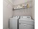 Efficient laundry area with modern washer and dryer, complemented by overhead shelving for supplies at 6051 Sw 93Rd Cir, Ocala, FL 34481