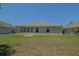 View of a spacious backyard with well-maintained lawn and the back of a home featuring multiple windows at 9068 Se 120Th Loop, Summerfield, FL 34491
