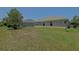 Wide backyard with green grass, trees, and a view of the back of a home with an enclosed patio at 9068 Se 120Th Loop, Summerfield, FL 34491