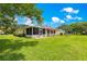 Spacious backyard featuring a lush lawn, screened patio and mature landscaping at 9891 Se 138Th Loop, Summerfield, FL 34491